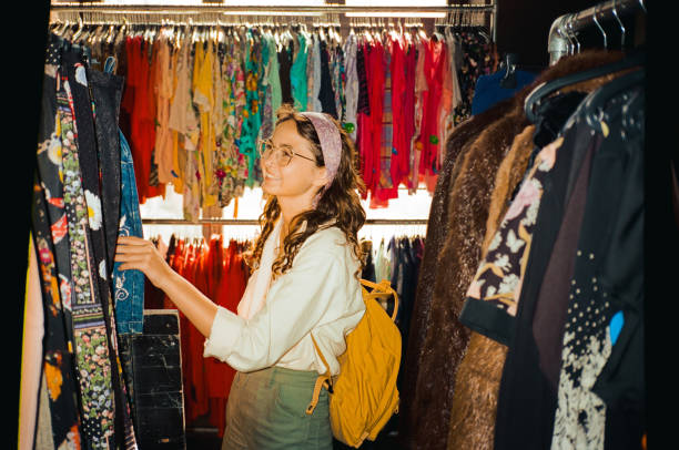 A woman explores a vibrant selection of vintage clothing in a store, blending modern style with classic pieces.